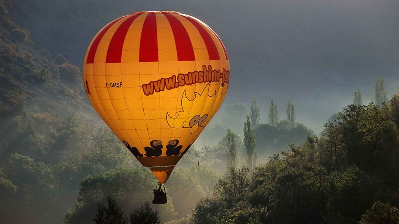 Hot air balloon over misty valley