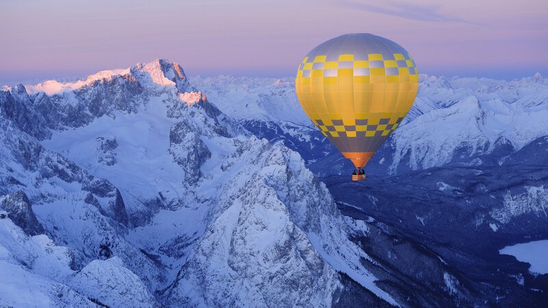 Hot air balloon over snowy mountains