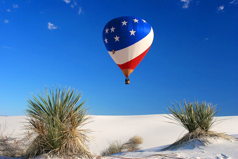 Hot air balloon over white dunes