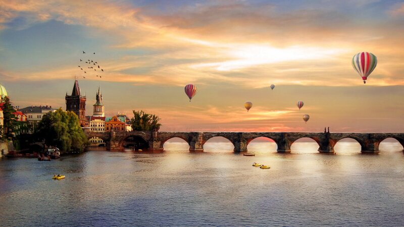 Hot air balloons over a historic bridge