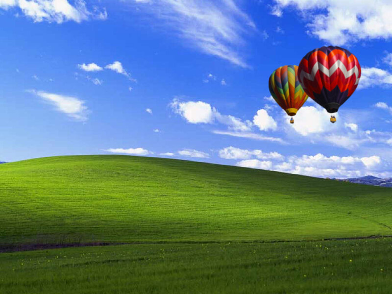 Hot air balloons over green hills