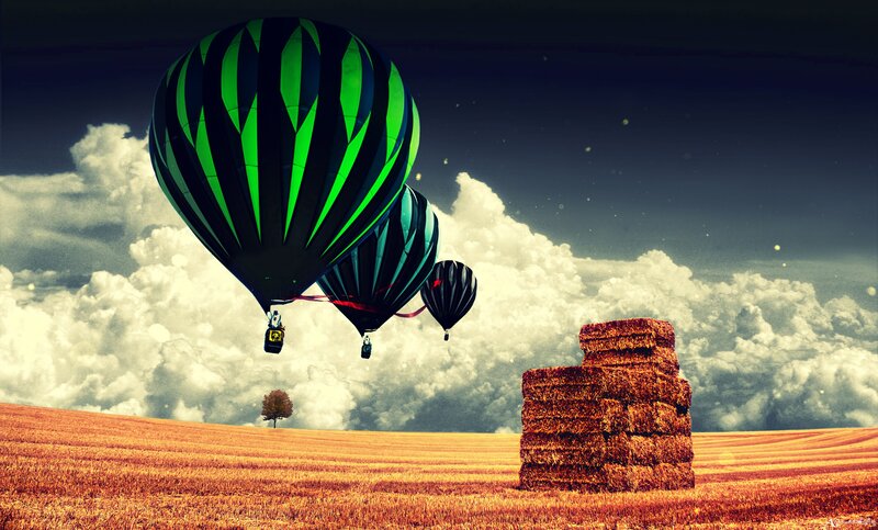 Hot air balloons over hay bales