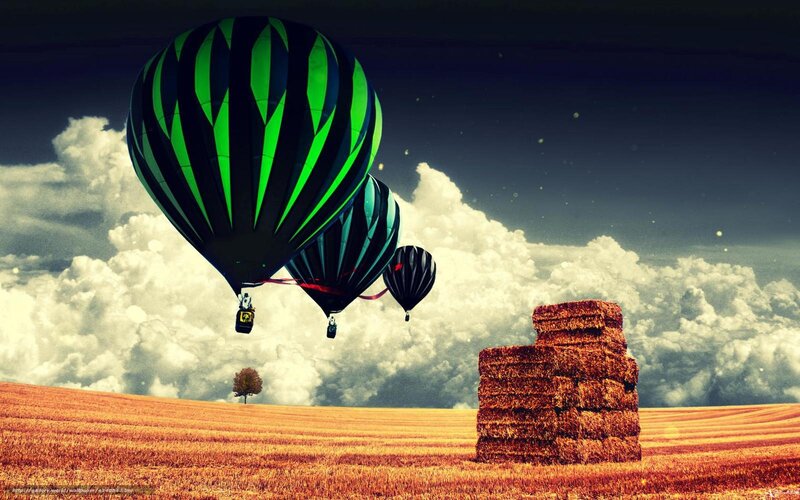 Hot air balloons over hay bales