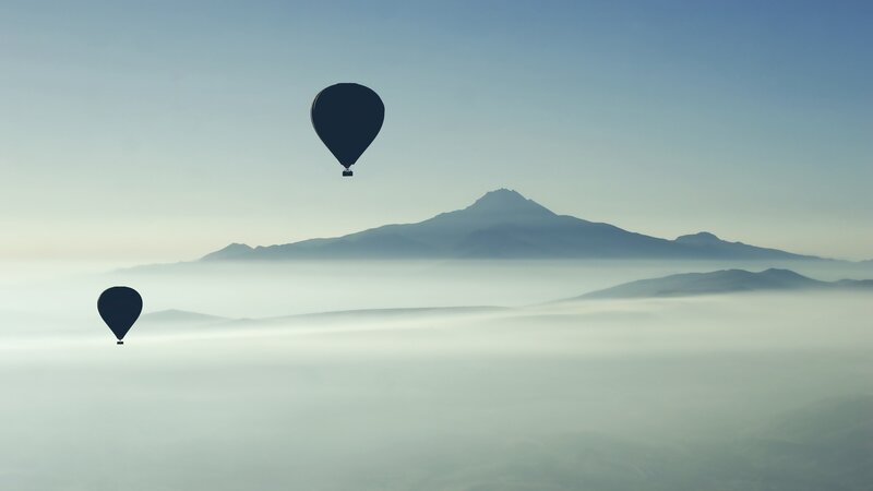 Hot air balloons over mountain fog