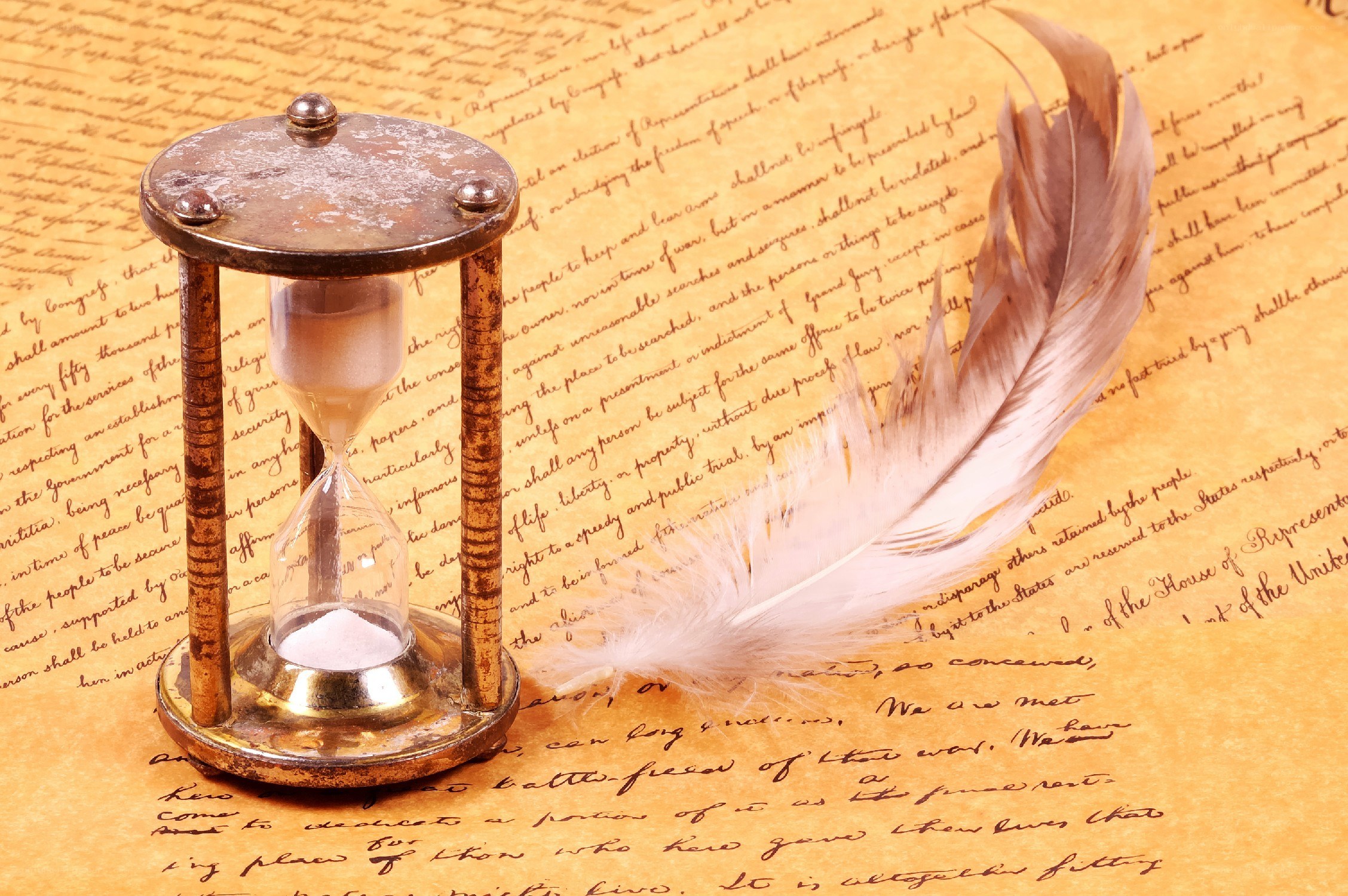 Hourglass and feather on parchment