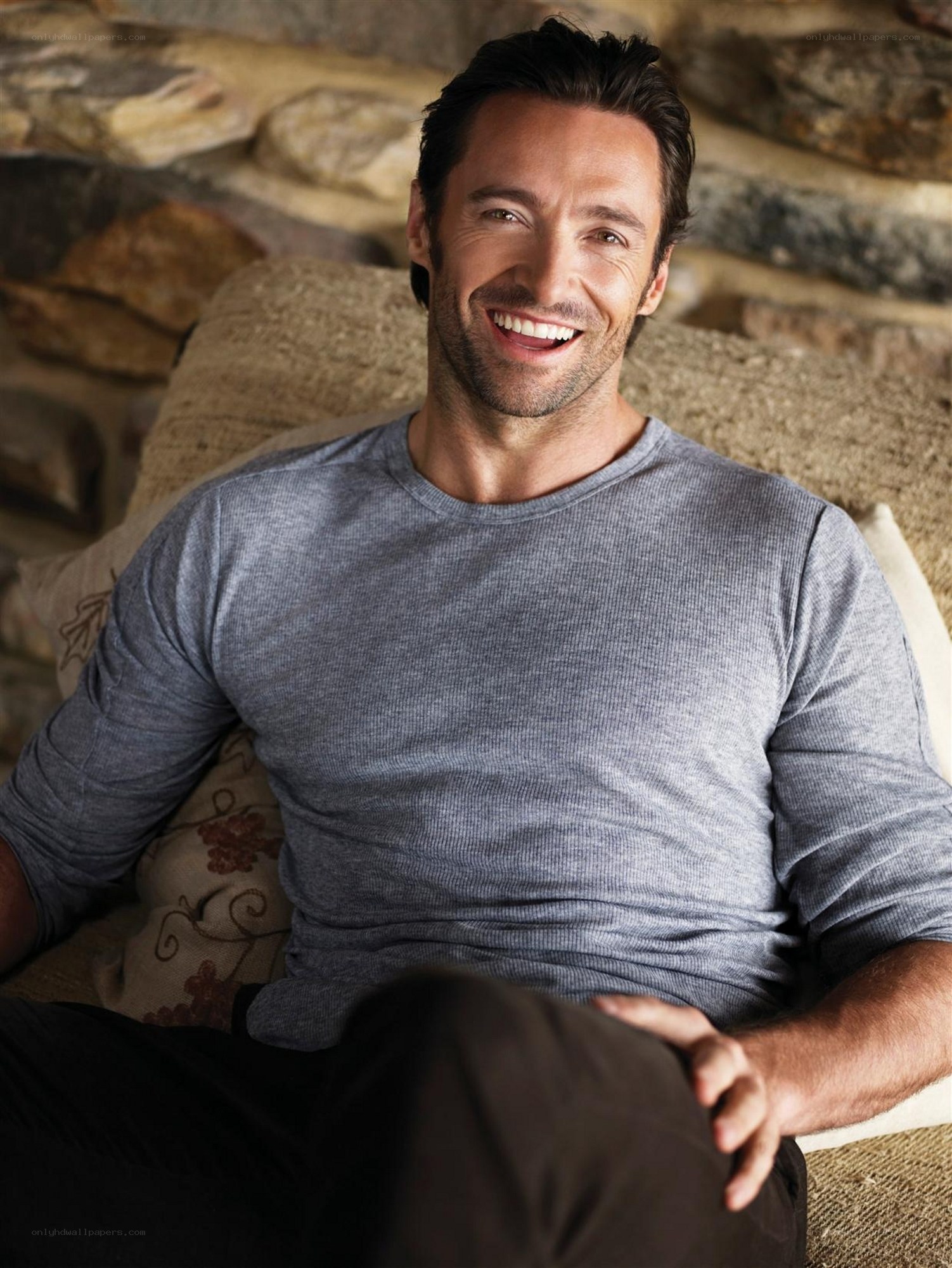 Hugh Jackman smiling on a couch