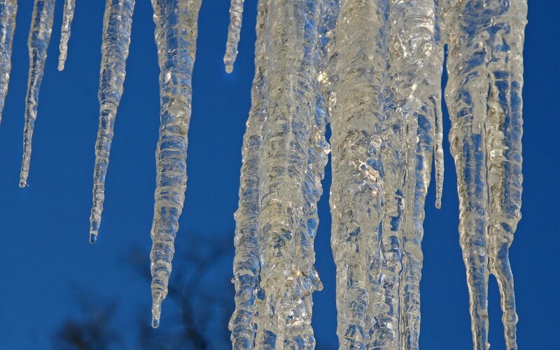 Icicles hanging against blue sky