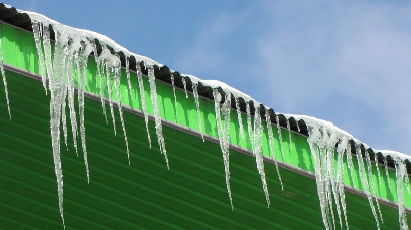 Icicles hanging from a green roof
