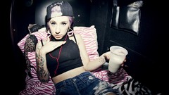 Music woman rapper tank tops tattoos lying down denim shorts 