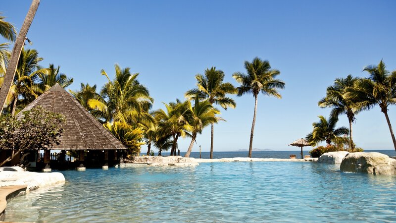 Infinity Pool at Resort — Blue, Serene, Afternoon, Photograph, Palm Trees, Thatched Hut, Ocean, Rocks