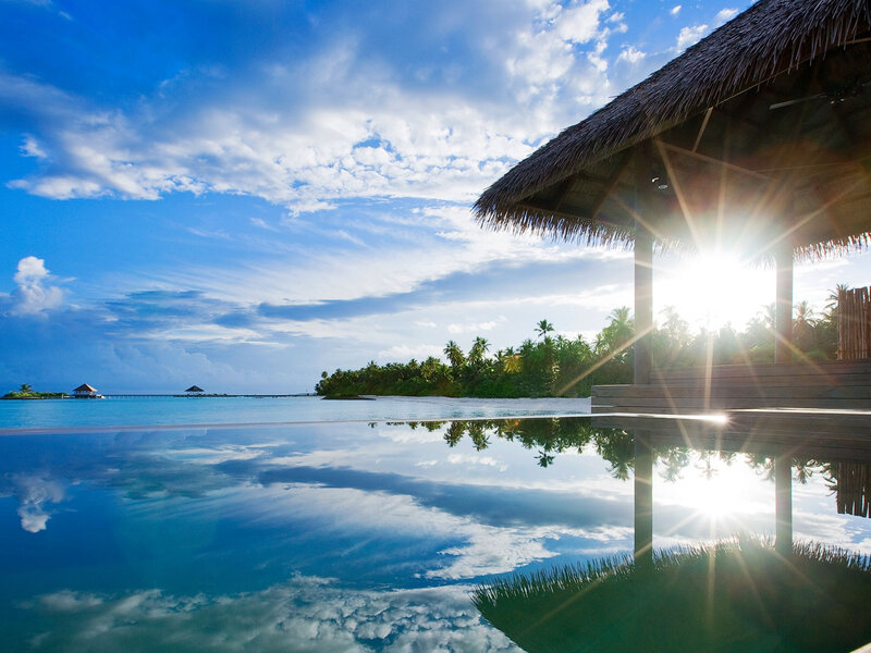 Infinity Pool at Resort — Blue, Serene, Sunset, Photograph, Thatched Roof