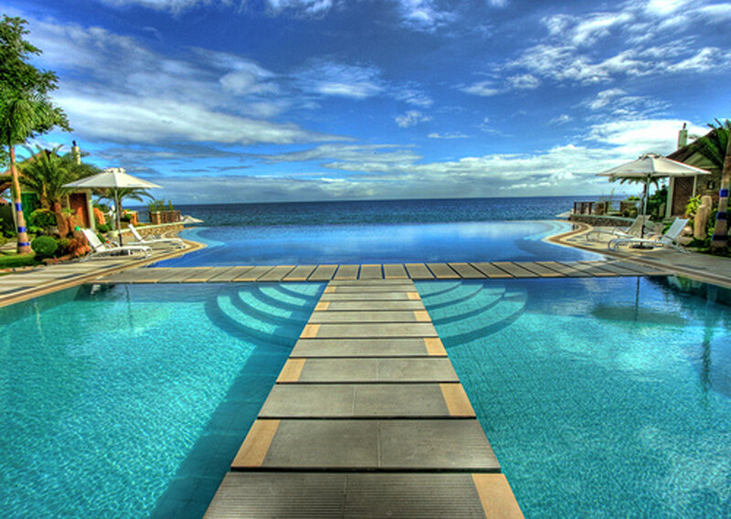 Infinity Pool Overlooking Ocean — Blue, Serene, Afternoon, Photograph, Umbrellas