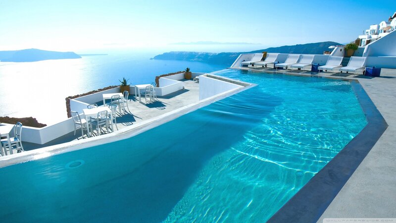 Infinity Pool Overlooking Sea — Blue, Serene, Afternoon, Photograph, Chairs, Ocean, Buildings