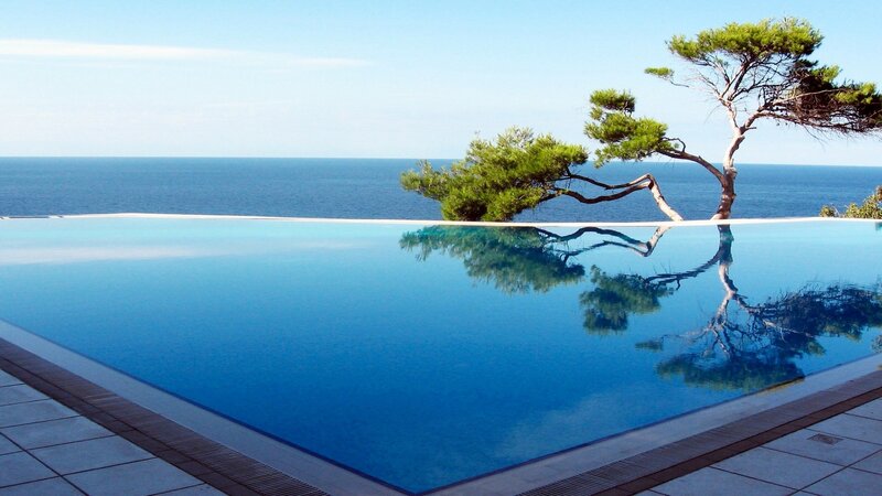Infinity Pool Overlooking Sea — Blue, Serene, Afternoon, Photograph, Tree, Ocean, Sky