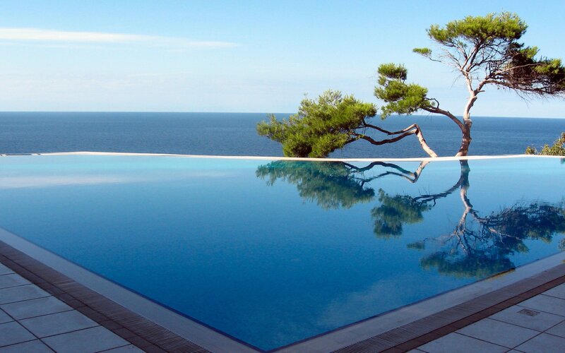 Infinity Pool Overlooking Sea — Blue, Serene, Afternoon, Photograph, Tree, Ocean