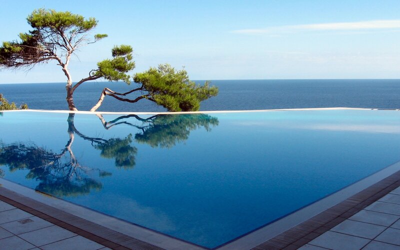 Infinity Pool Overlooking Sea — Blue, Serene, Afternoon, Photograph, Tree