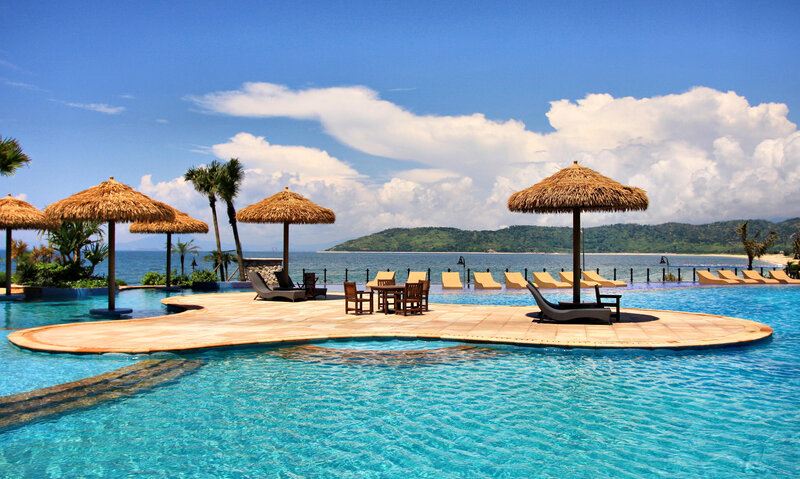 Infinity Pool with Lounge Chairs — Blue, Serene, Afternoon, Photograph, Thatched Umbrellas