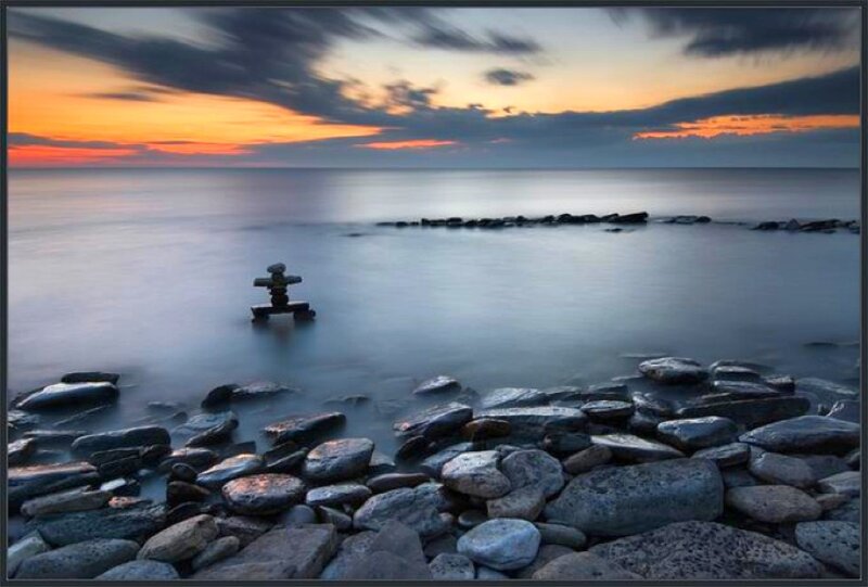 Inukshuk at sunset on a rocky shore