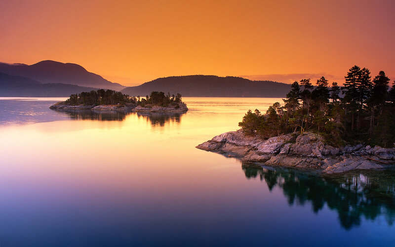 Island in Calm Water — Orange, Serene, Sunset, Photograph, Mountains, Trees, Sky, Blue, Green