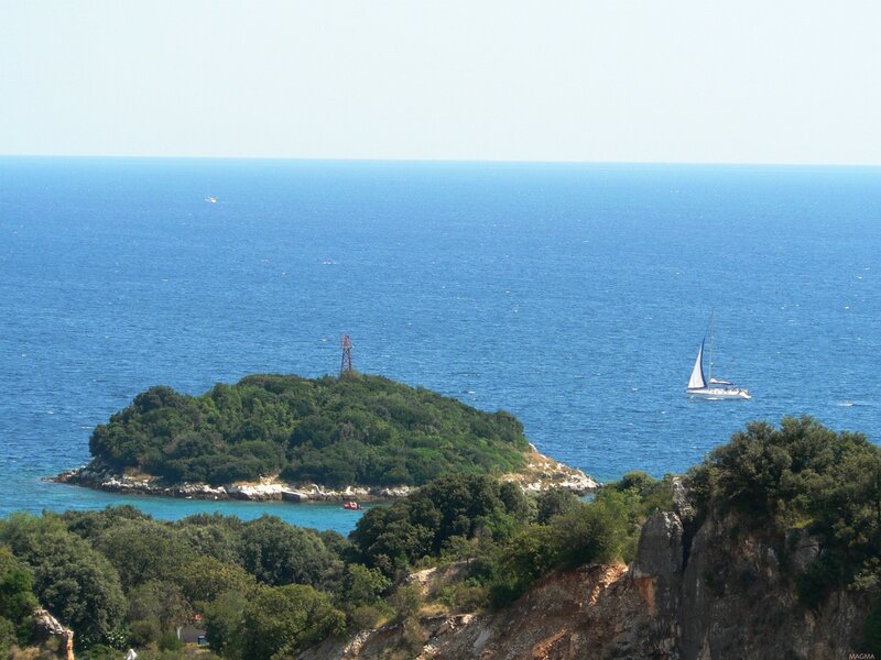 Island with sailboat in blue sea