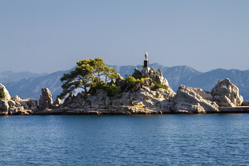 Island with statue and mountains