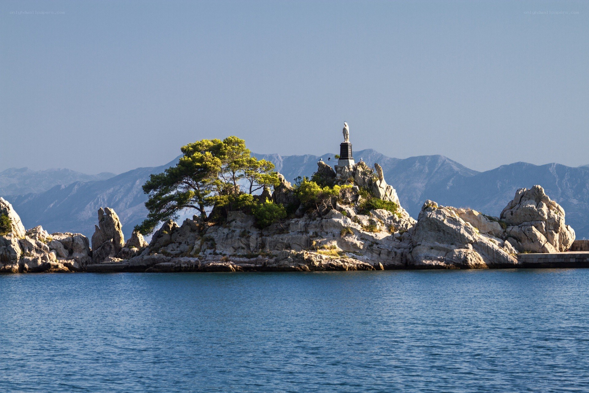 Island with statue and mountains