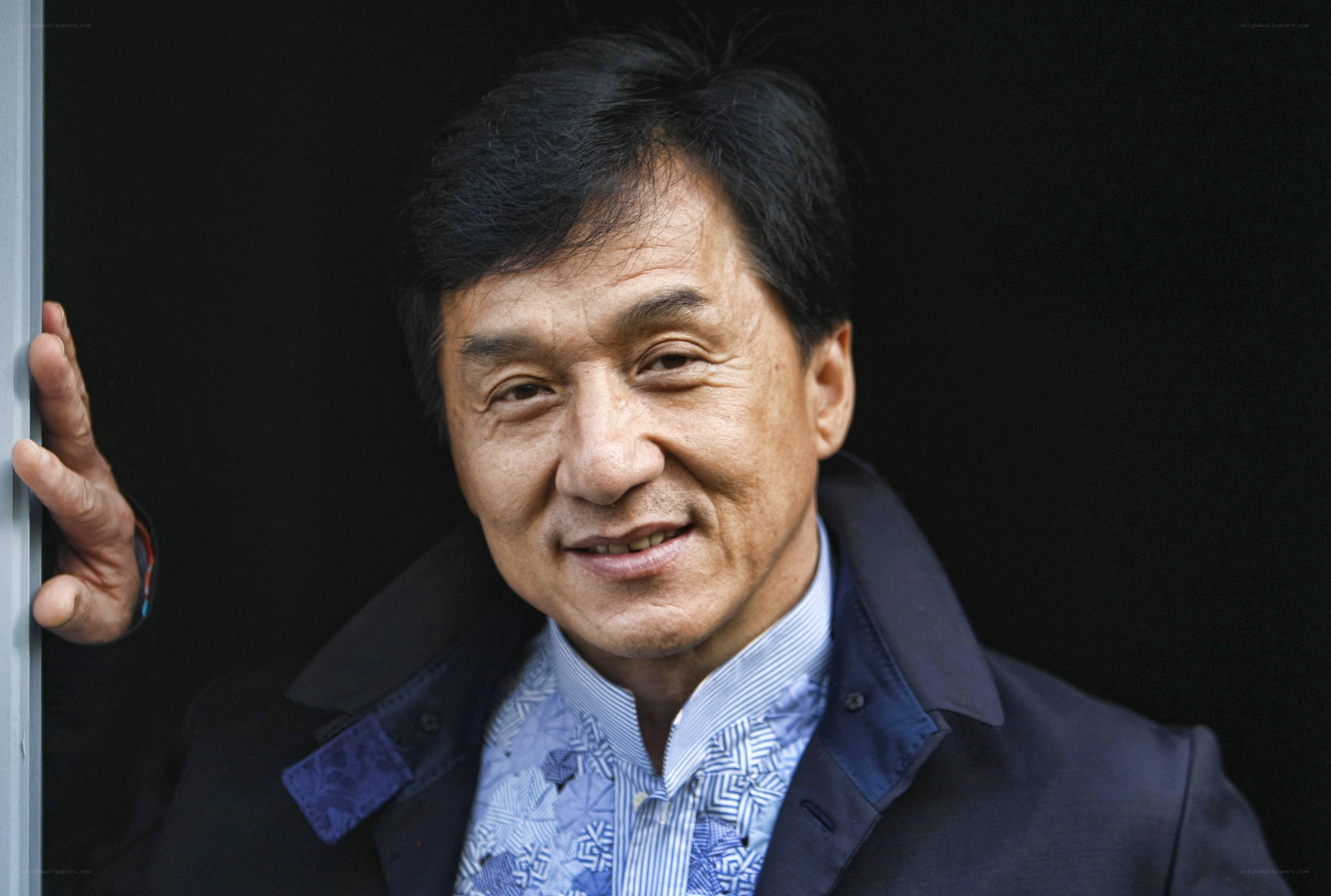 Jackie Chan smiling in a suit
