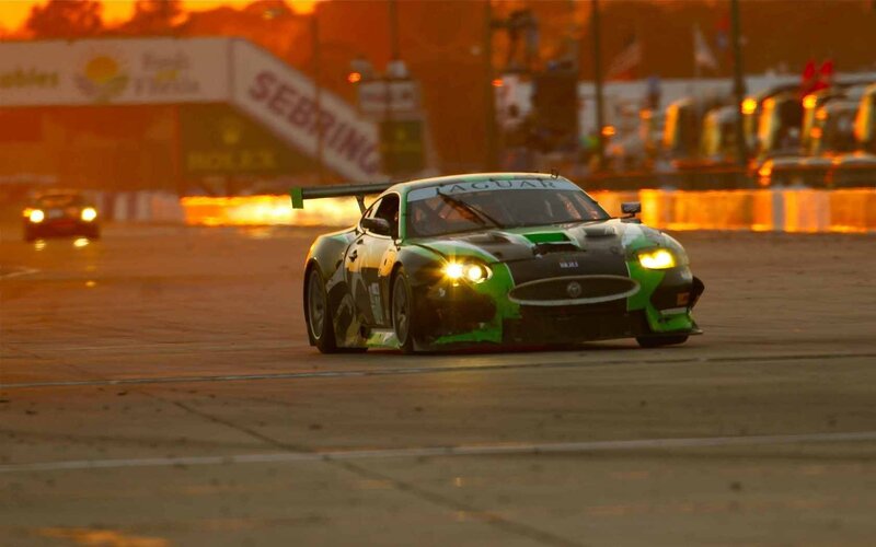 Jaguar race car on track at sunset