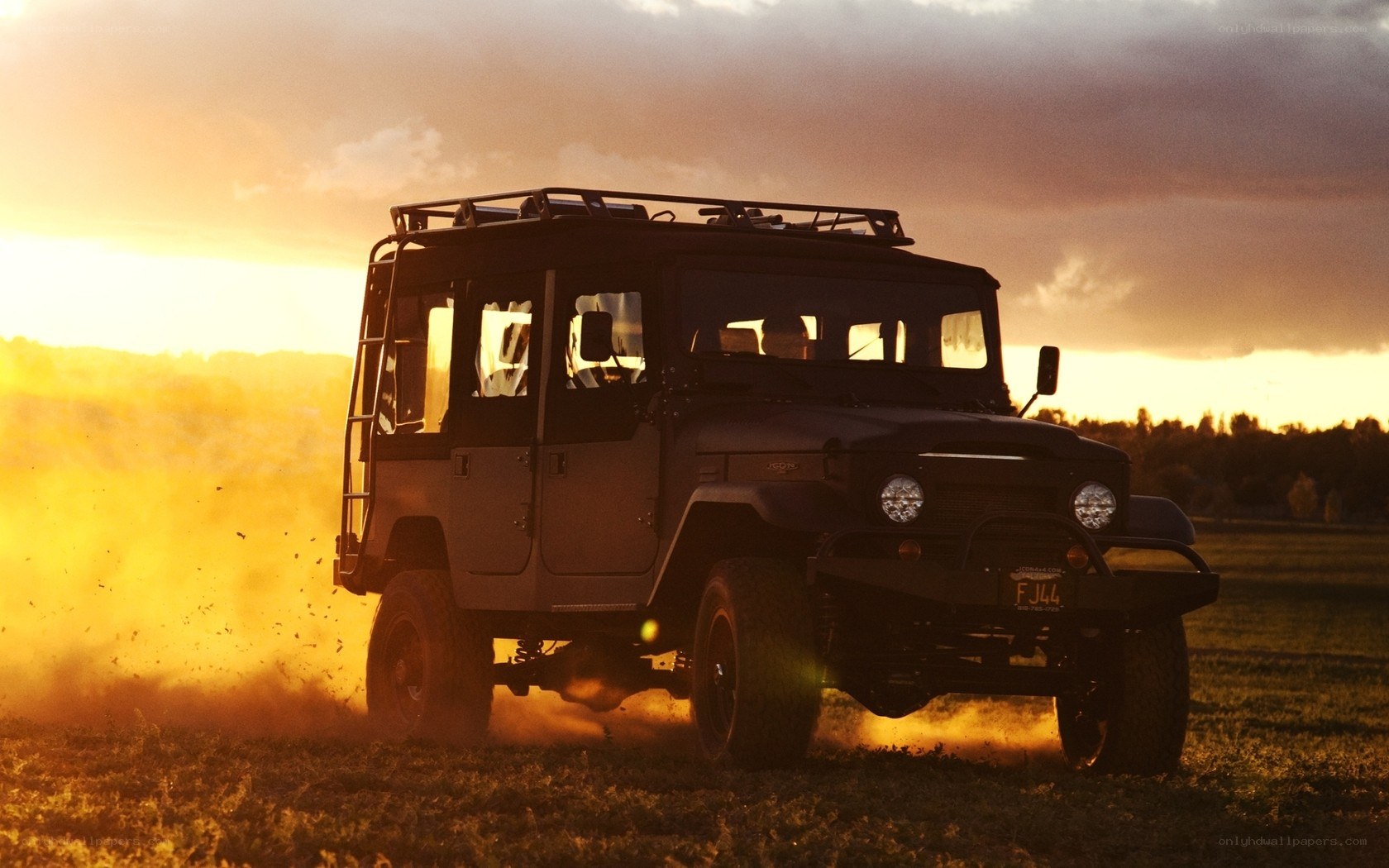Jeep driving in a field at sunset