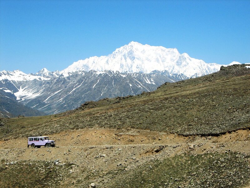 Jeep on mountain road with snow-capped peak