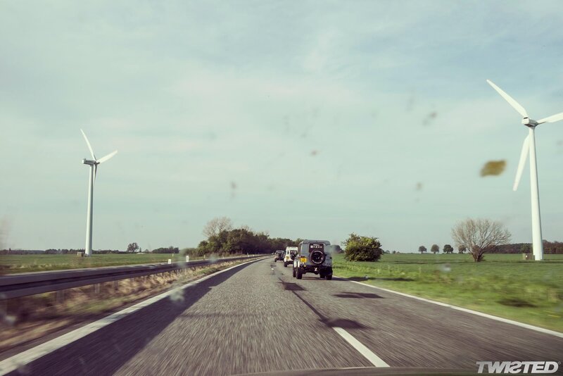 Jeeps on a road with wind turbines