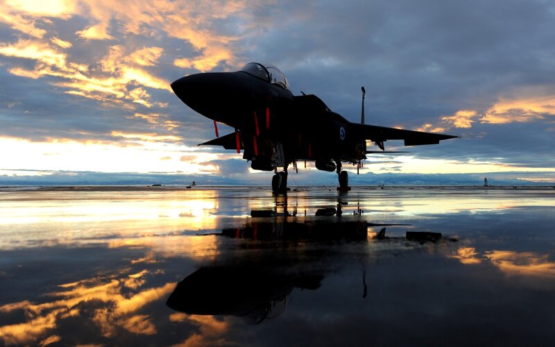Jet fighter on wet tarmac at sunset