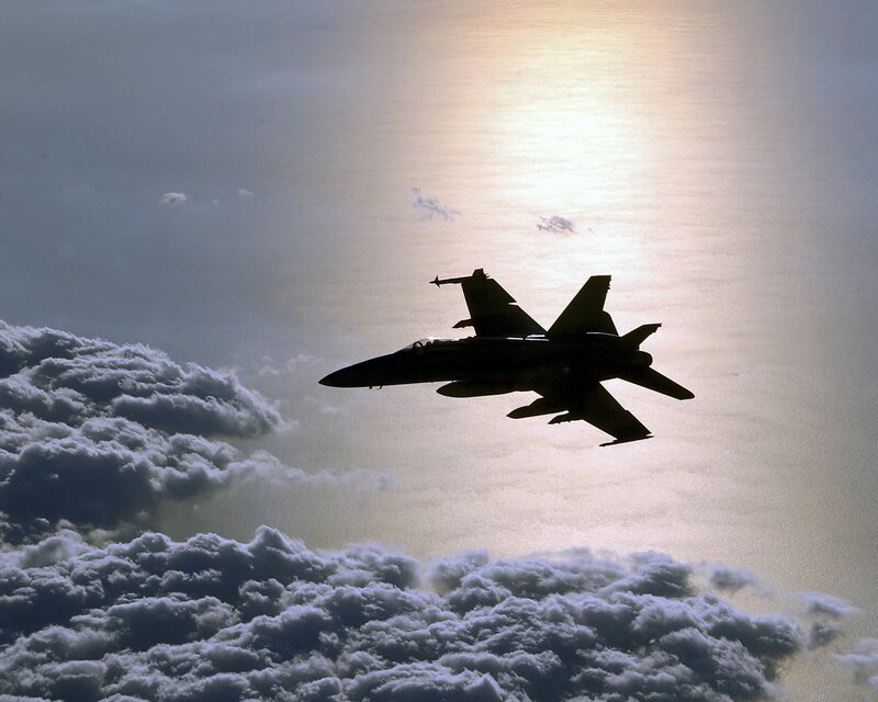 Jet fighter silhouetted against sun