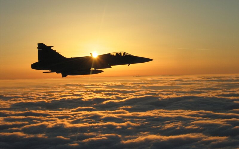 Jet flying above clouds at sunset