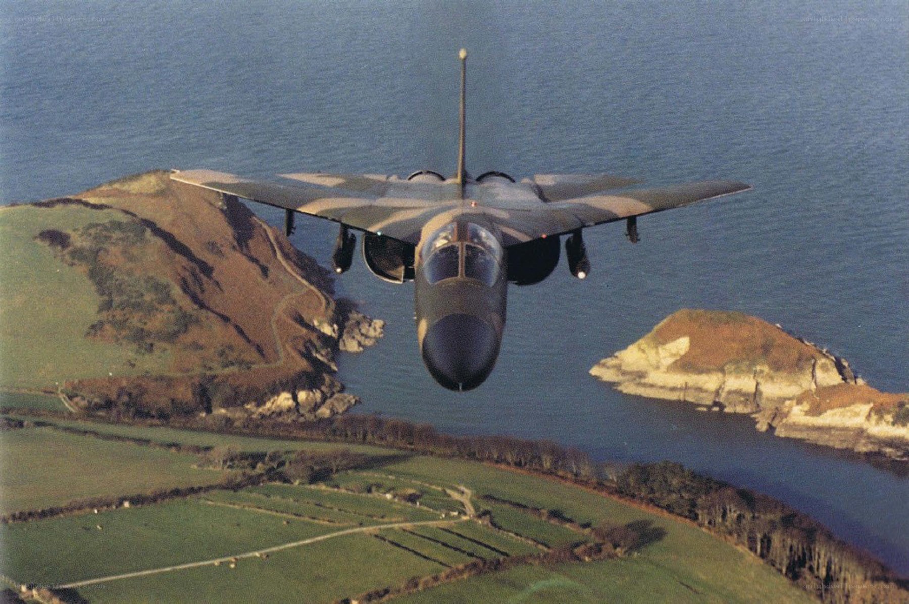 Jet flying over coastal landscape