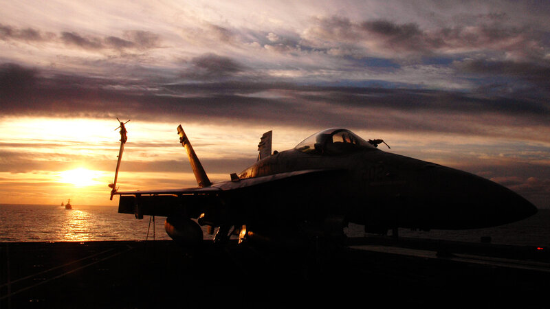 Jet on aircraft carrier at sunset