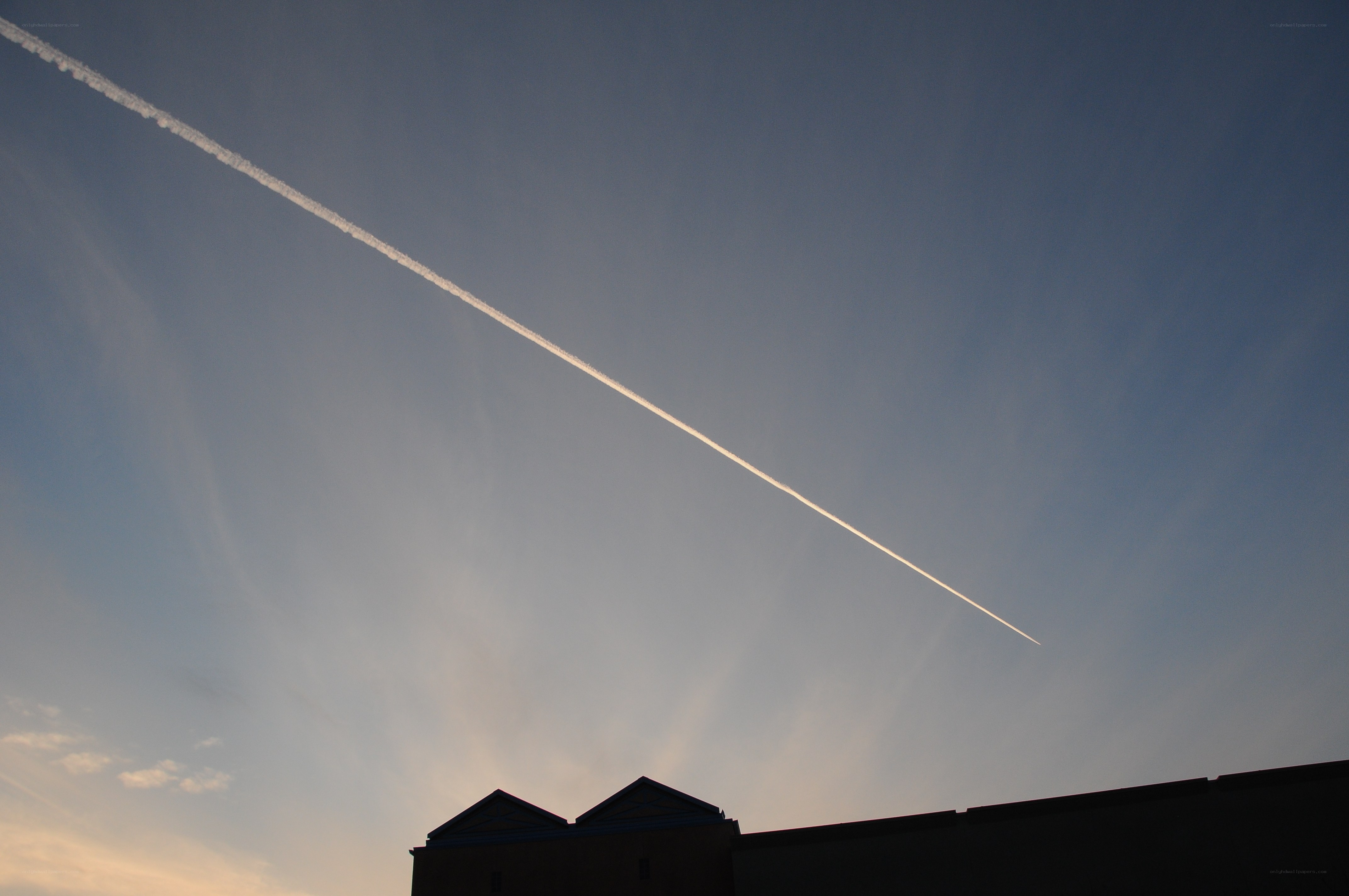 Jet stream over building silhouette