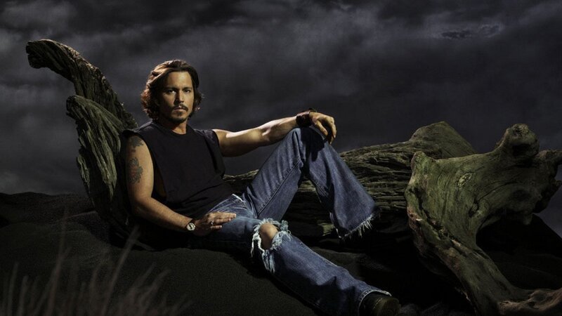 Johnny Depp sitting on driftwood