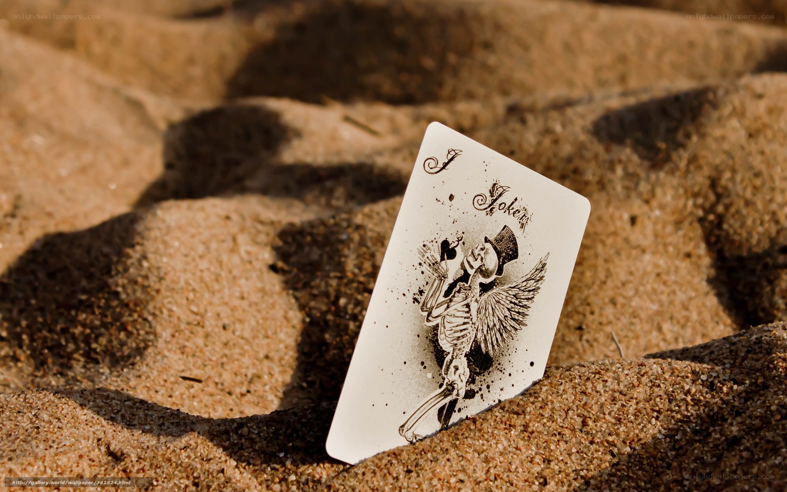 Joker card in sand