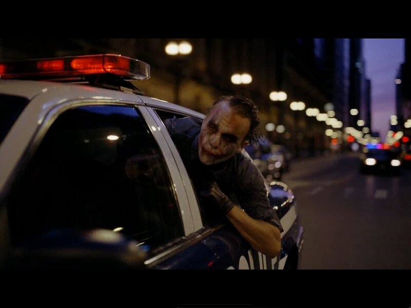 Joker leans from police car