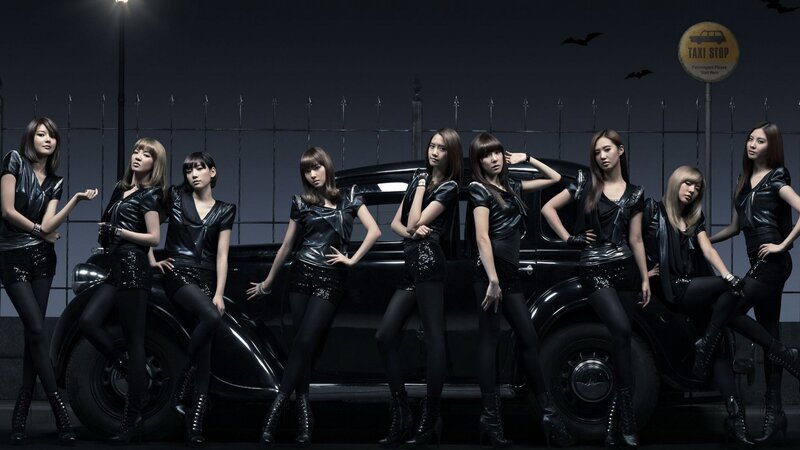 K-pop group posing with vintage car