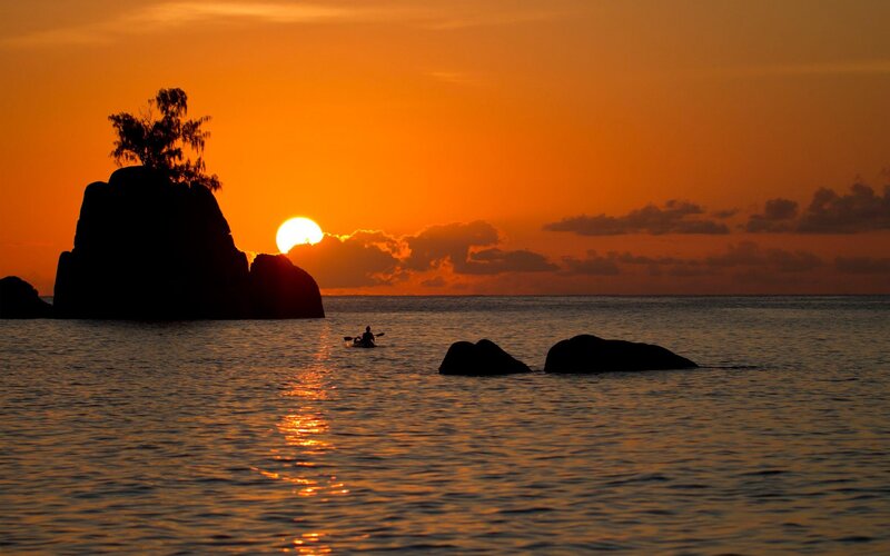 Kayaker at sunset by rocks