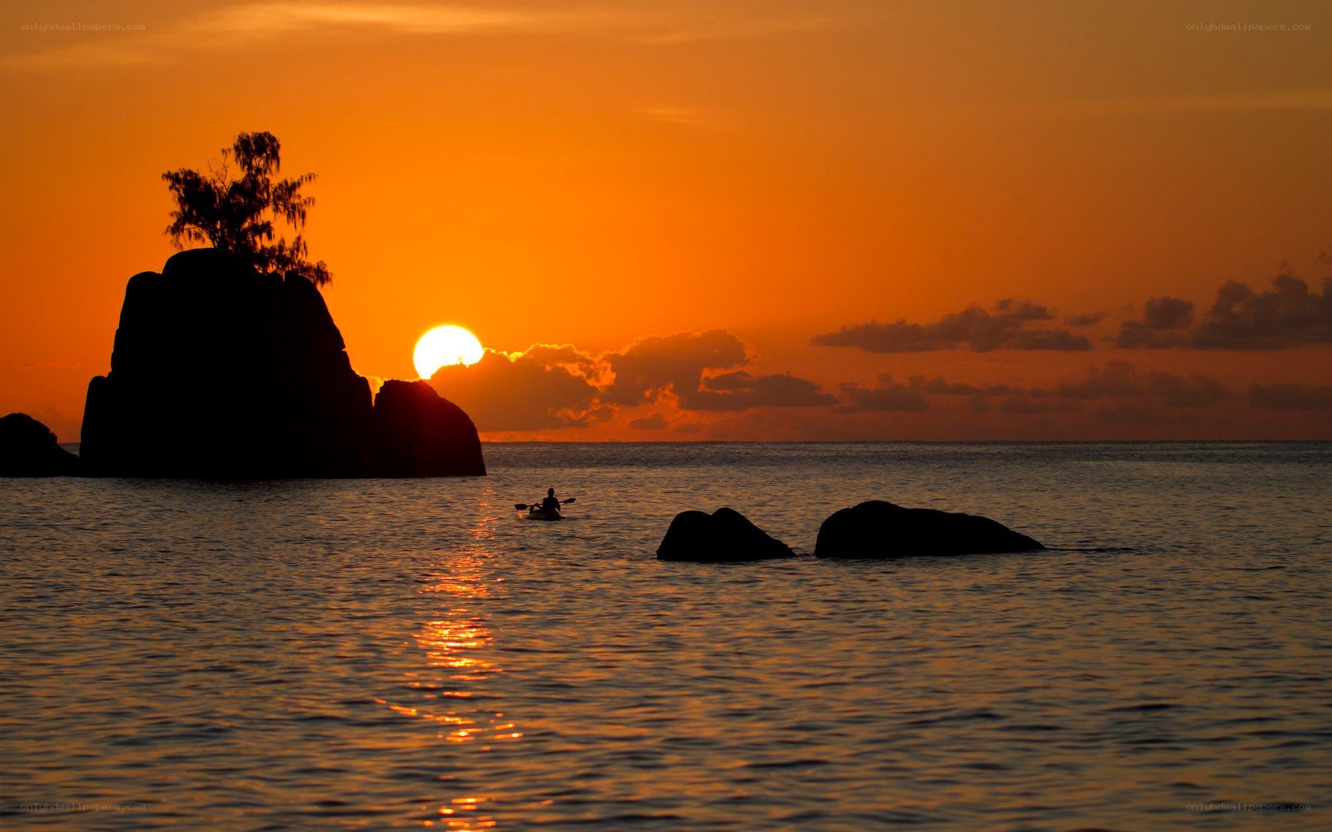 Kayaker at sunset by rocks