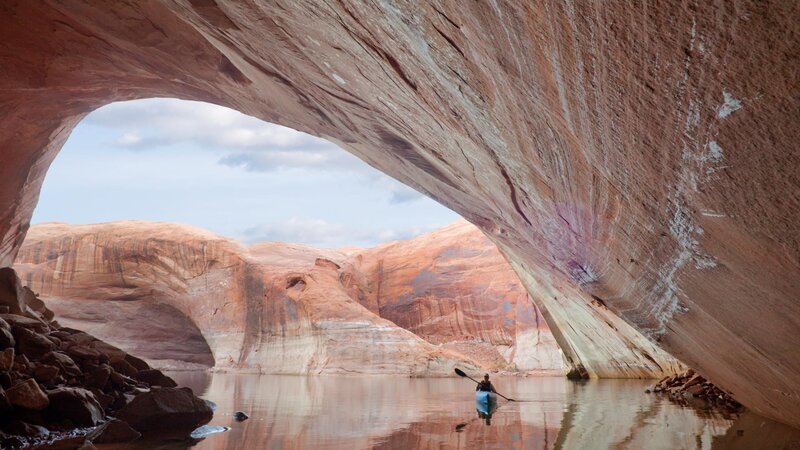 kayaker under rock arch