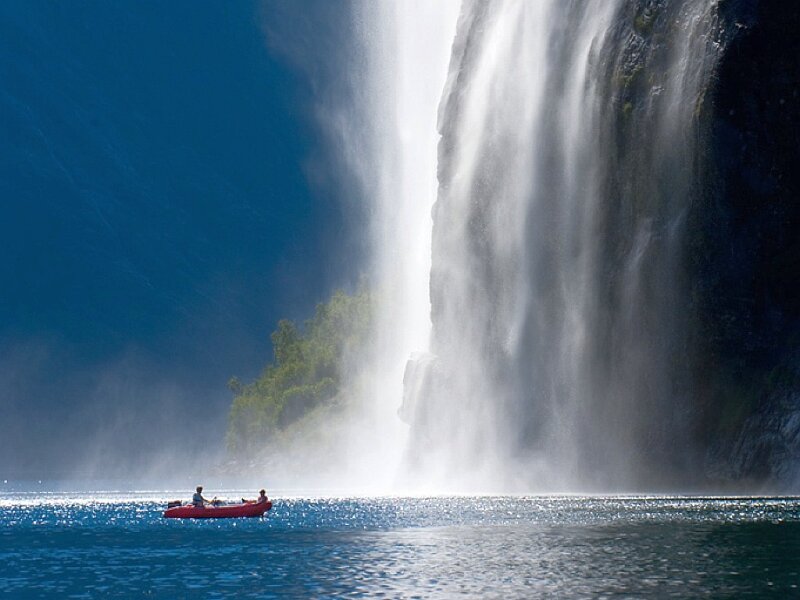 Kayakers near a massive waterfall