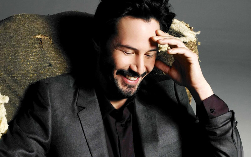 Keanu Reeves smiling in suit