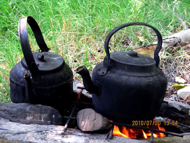 Kettles boiling over campfire