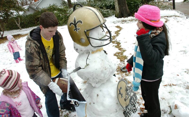 Kids building snowman with Saints helmet