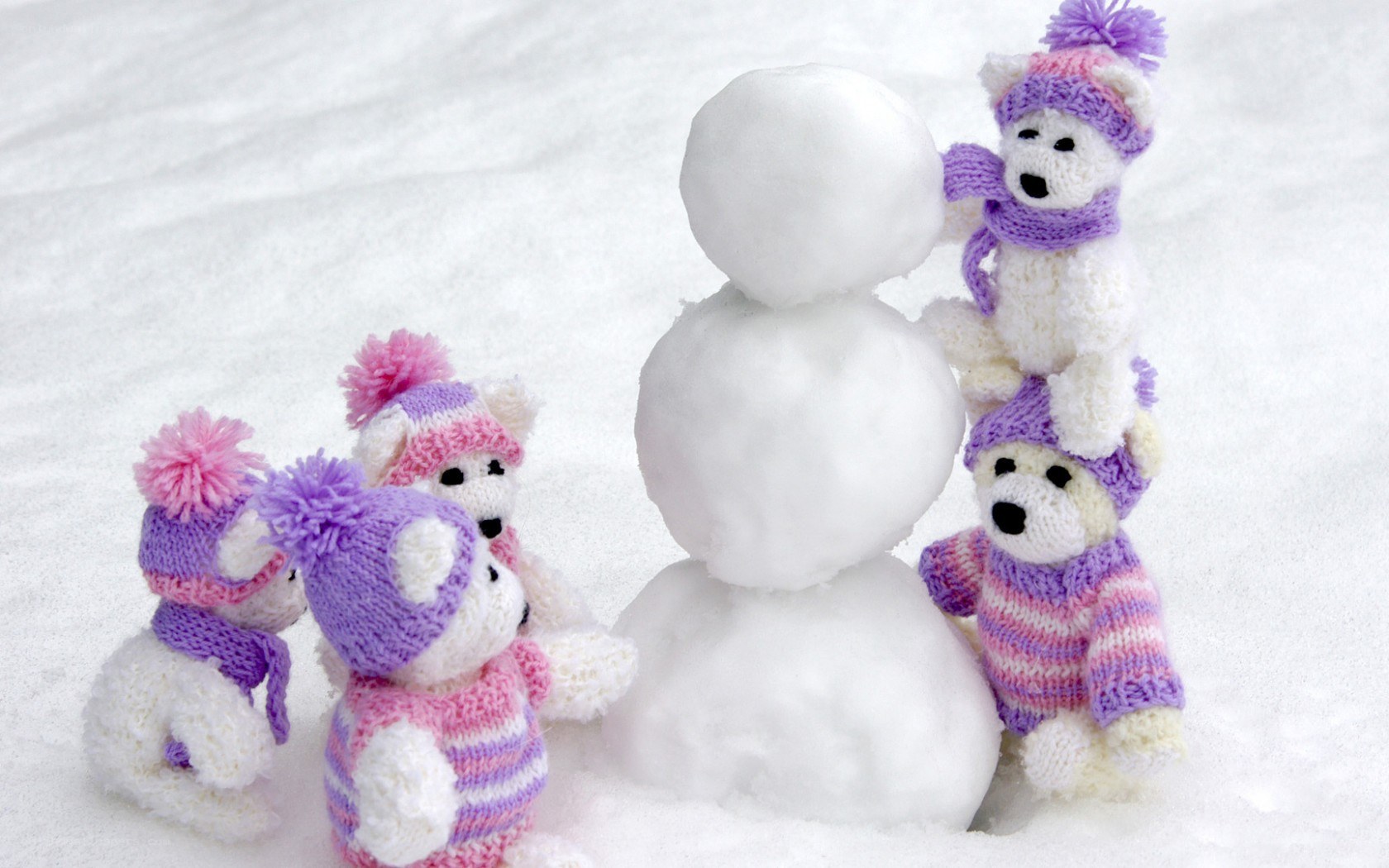 Knitted bears building snowman