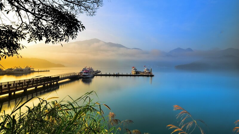 Lake dock at sunrise with misty mountains